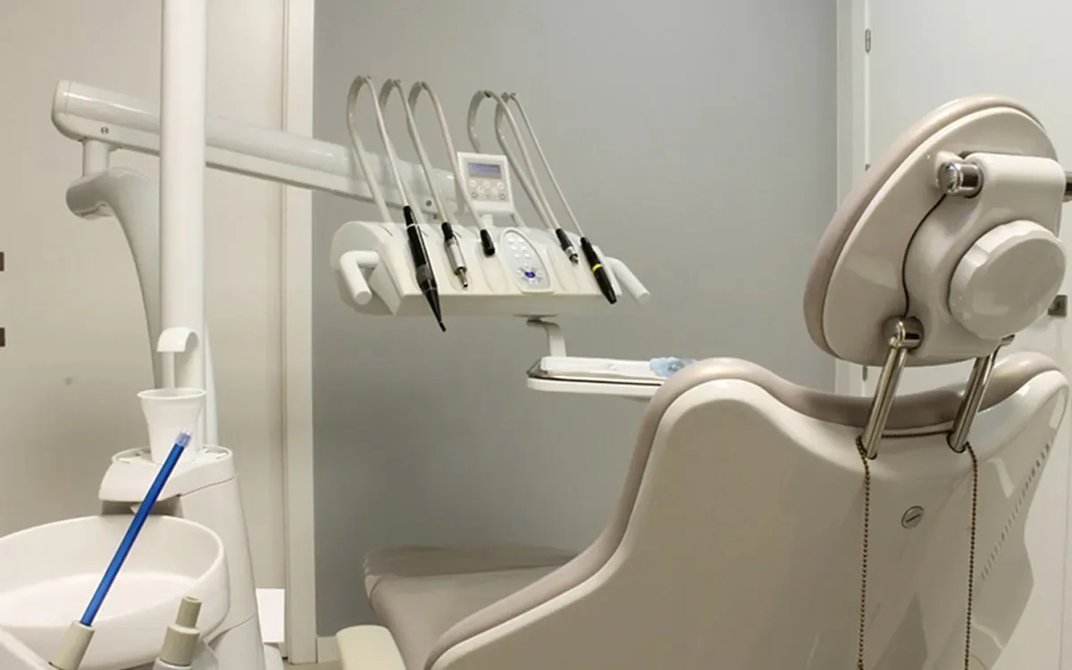 A well lit dentist office, showing the back of a dentist chair.